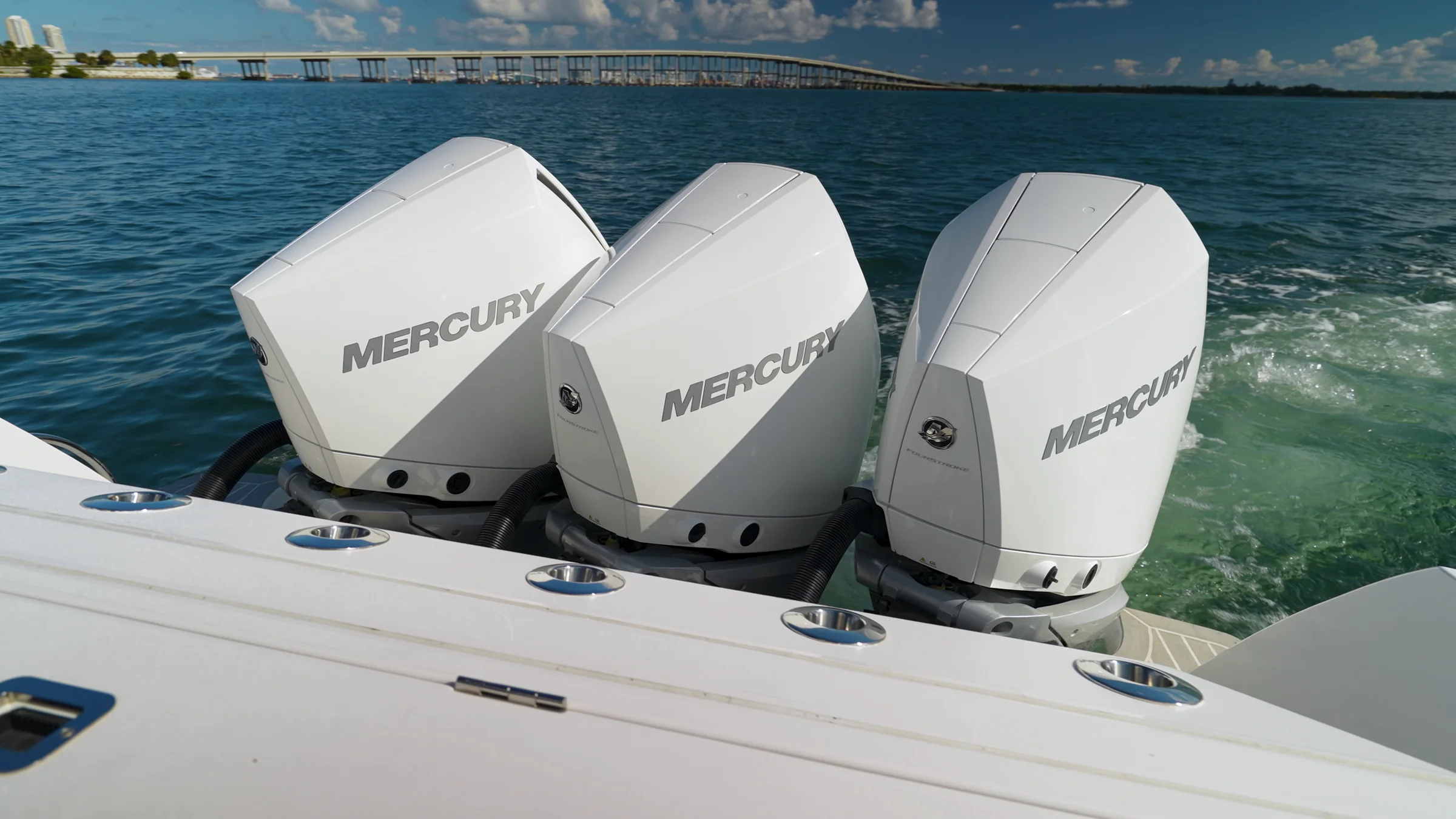 Three white Mercury outboards on the transom, sea running past