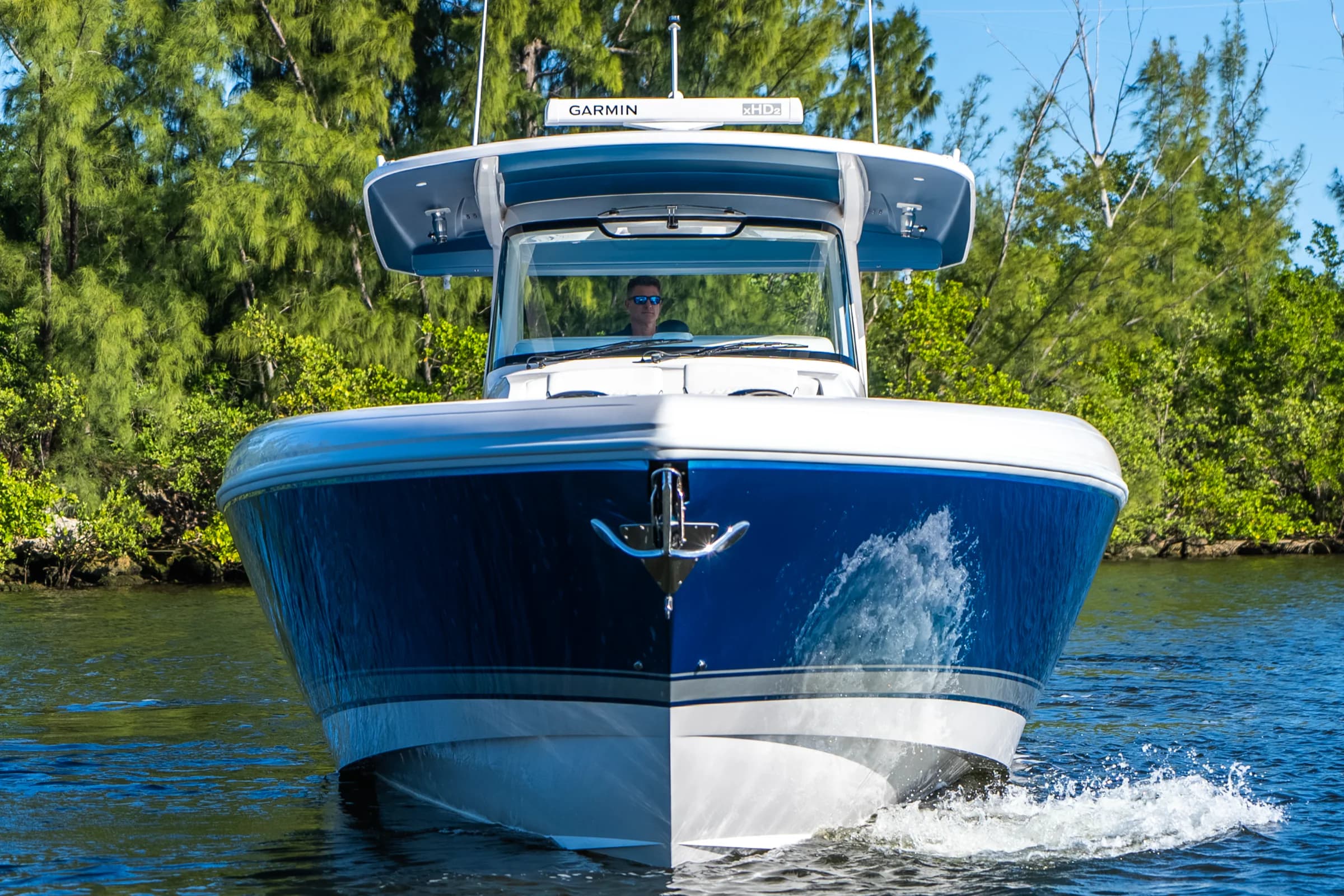 An Intrepid center console approaching head-on through calm water, mangroves behind