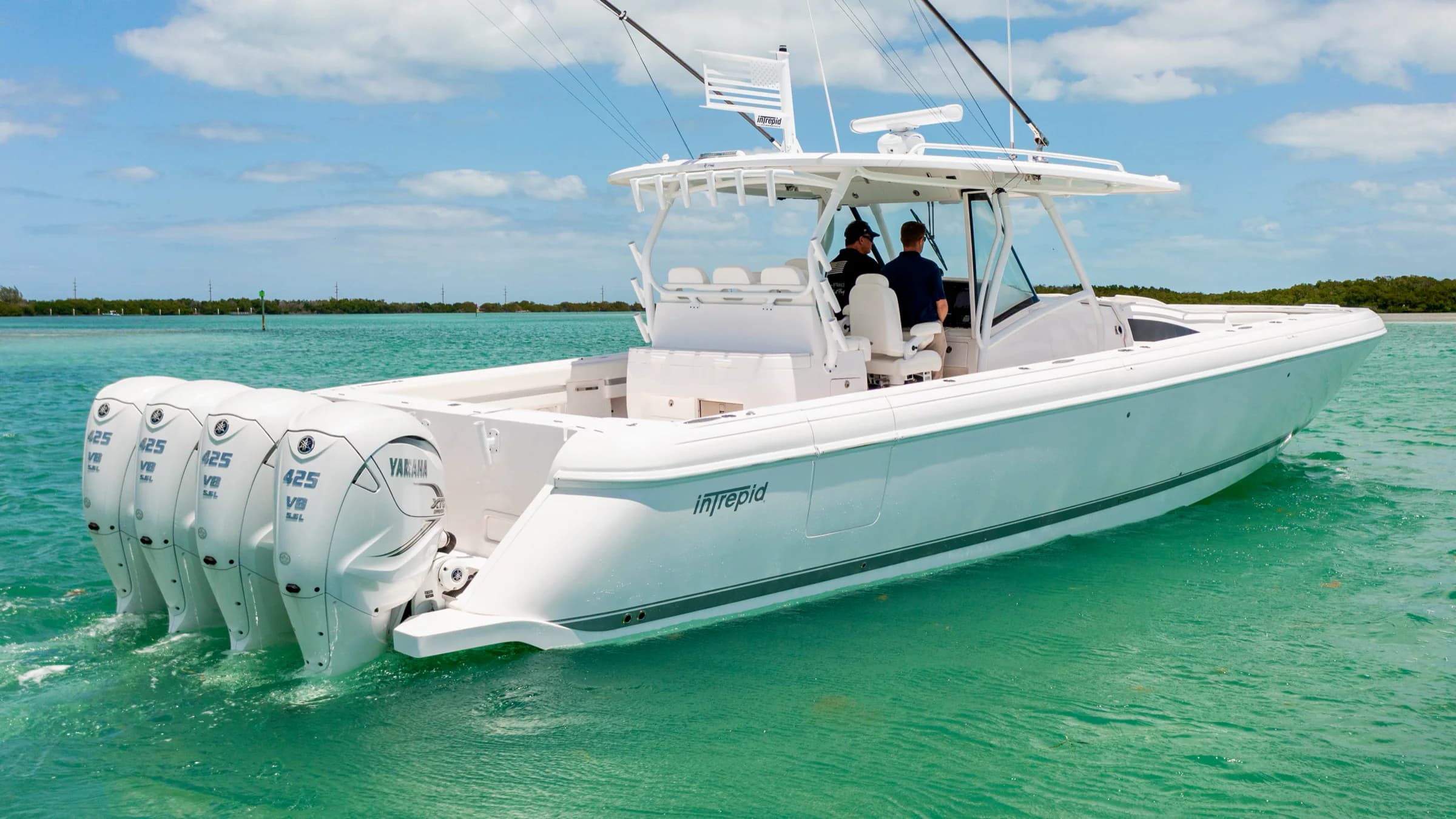 An Intrepid with four outboard engines at rest in shallow turquoise water