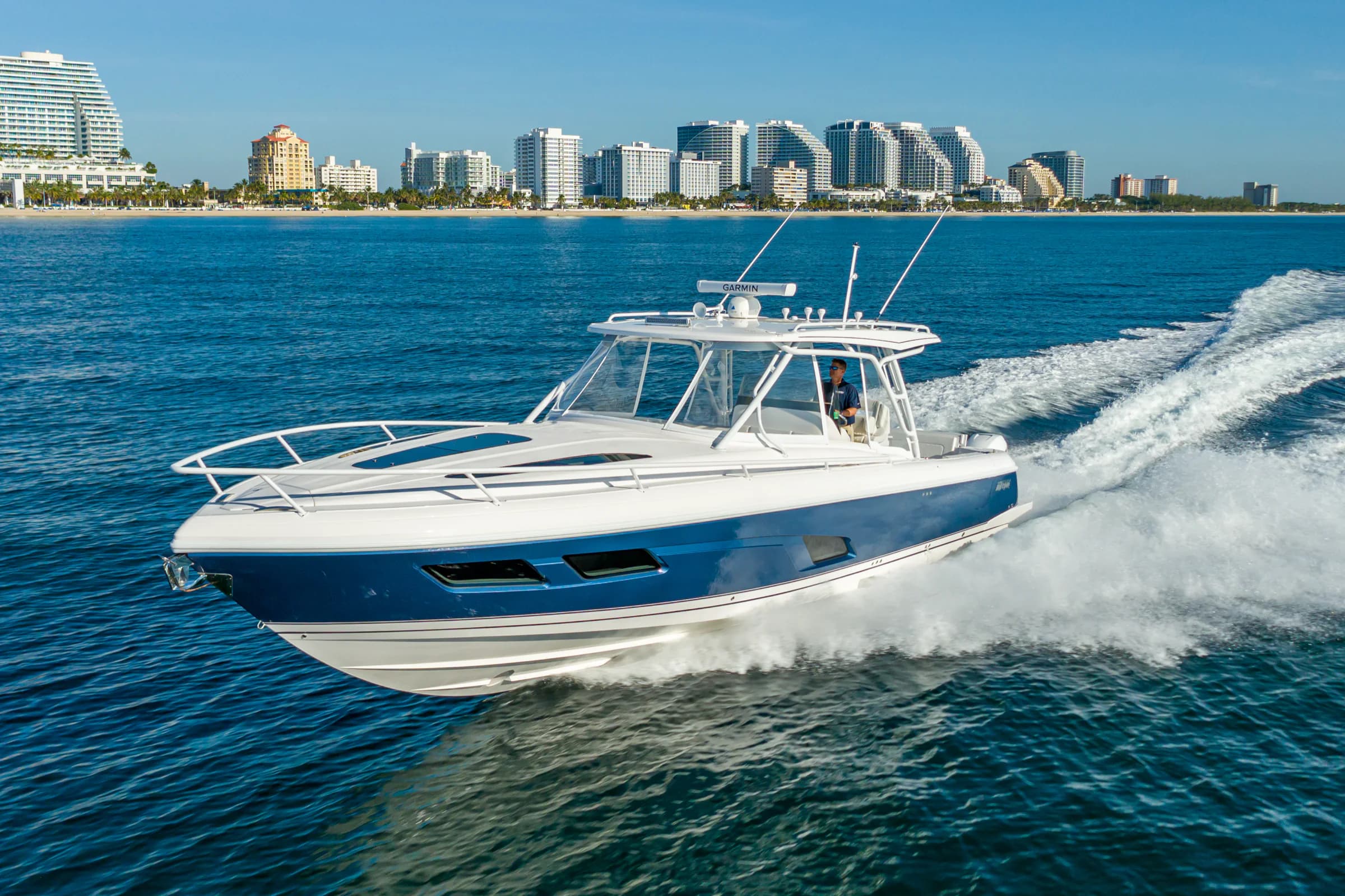 A blue-hulled Intrepid center console running at speed past a city skyline