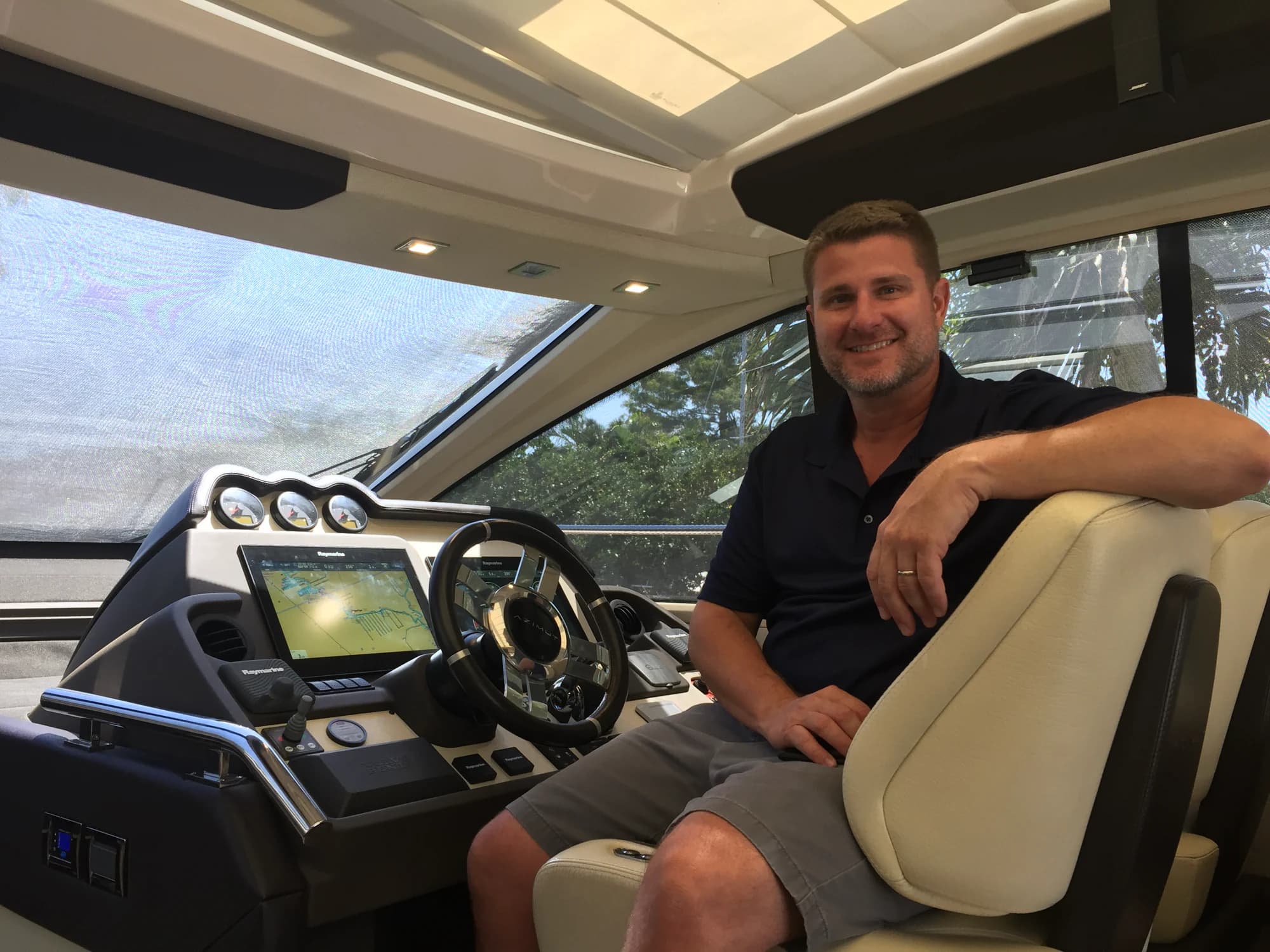 Paul Keeney seated at the helm of a yacht, smiling